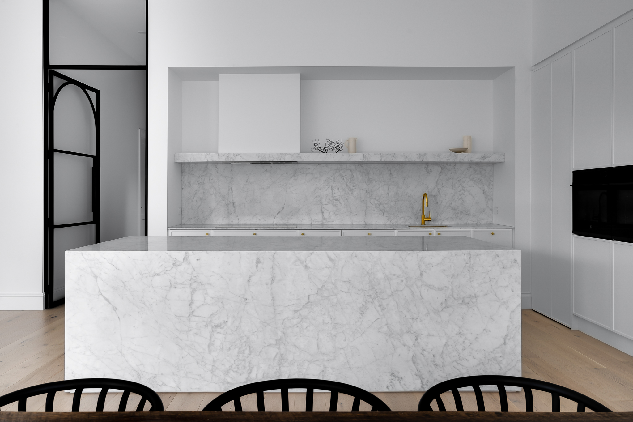 Font view of marble kitchen benchtops, island benchtop and splashbacks featuring Carrara Marble
