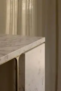 Close-up of a white marble countertop with subtle gray veining atop a matching cabinet edge.