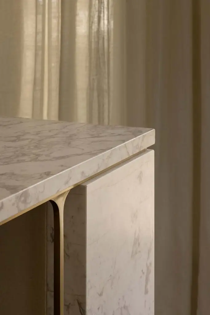 Close-up of a white marble countertop with subtle gray veining atop a matching cabinet edge.