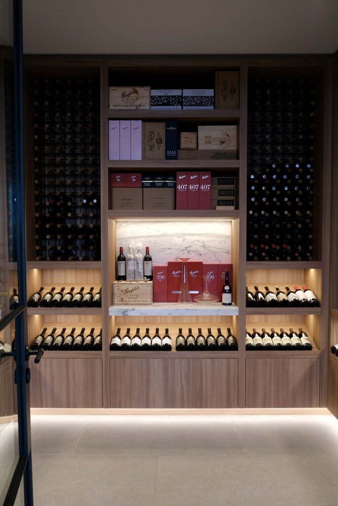 Wooden wine display with multiple shelves filled with bottles and boxed wines, soft backlighting in a modern shop setting